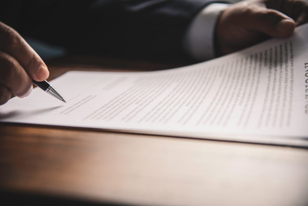 image for our policy page Hand holding pen signing contract in important documents.