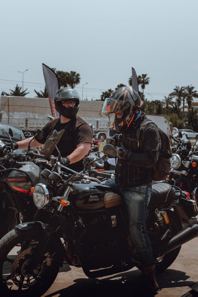 Two bikers in helmets and jackets prepare for a ride on vintage motorcycles. for motorcycle club culture record article