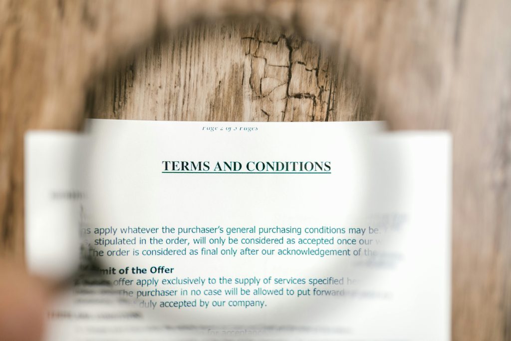 Magnifying glass focusing on terms and conditions document on a wooden surface. for the terms of use page